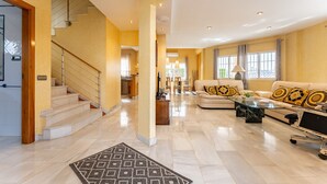 A spacious living area with a staircase, a sofa set, and a dining area.