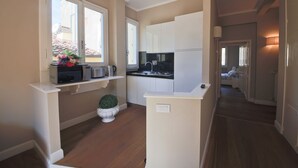 Une cuisine de taille réduite avec des meubles blancs, un four à micro-ondes et une petite plante en pot.