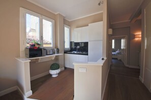A compact kitchen with white cabinets, a microwave, and a small potted plant. - Apartments Florence- Barbadori Apartment (Firenze)