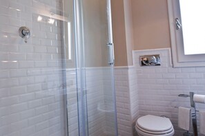 A bathroom with white tiled walls, a glass shower enclosure, a toilet, and a towel rack. - Apartments Florence- Barbadori Apartment (Firenze)