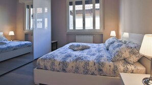 Une chambre à coucher avec un lit, deux lampes de chevet, une fenêtre et un radiateur.