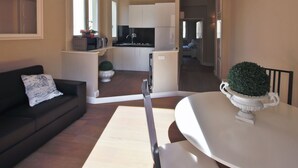 Un salon moderne avec un canapé, une table à manger et une cuisine en arrière-plan.