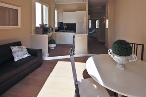 A modern living room with a sofa, a dining table, and a kitchen in the background. - Apartments Florence- Barbadori Apartment (Firenze)