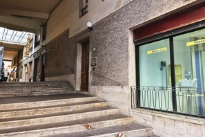 Un bâtiment avec un escalier menant à l’entrée, une enseigne indiquant « Posteitaliane », et une fenêtre donnant sur l’intérieur.
