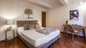 Une chambre à coucher comprenant un lit, des tables de chevet, un bureau, une chaise et des œuvres d’art accrochées aux murs.