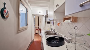 Una cocina estrecha con ventana, un lavamanos y una estufa.