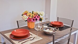 A dining table set with red plates, a glass, a metal bowl, and a vase with flowers. - Apartments Florence- Brunelleschi 1 bd (Firenze)