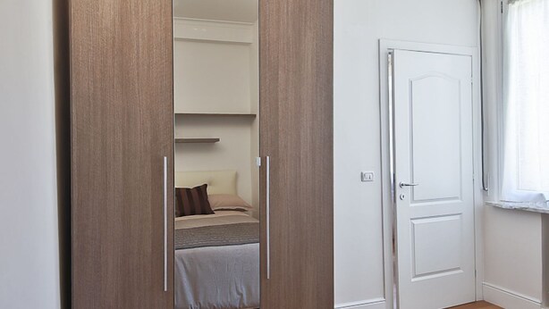 A bedroom with a bed, a wardrobe, and a door. - Apartments Florence- Brunelleschi 1 bd (Firenze)