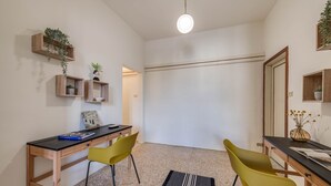 Een kamer met een bureau, twee gele stoelen, een zwart tapijt en houten planken met planten.