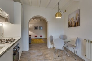 A modern kitchen with a gas stove, white cabinets, and a dining area with a glass table and chairs.