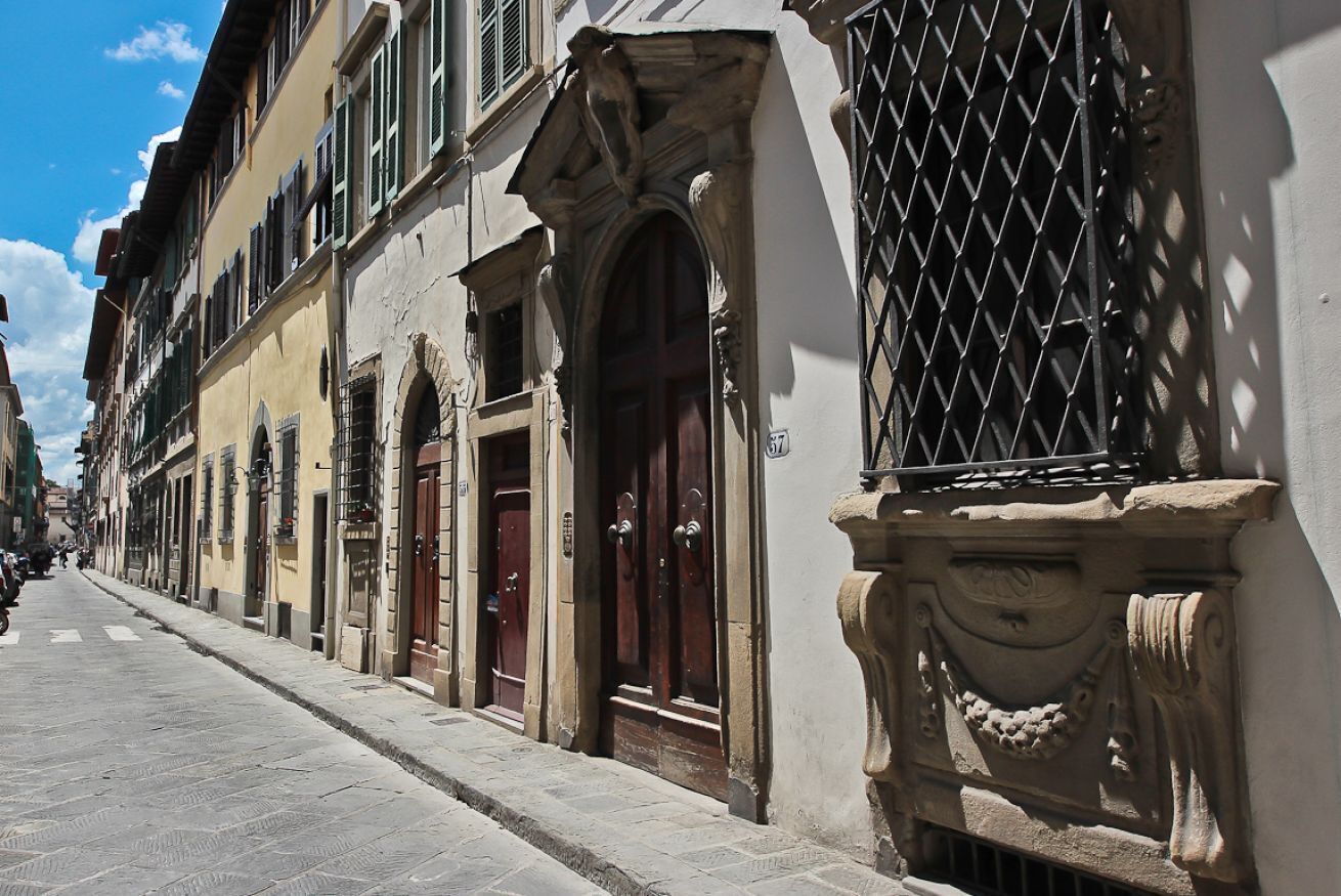 A narrow street lined with historic buildings featuring arched doorways and decorative stonework.