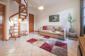 Una sala de estar con una escalera espiral, un sofá, una mesa de centro y un tapete grande.