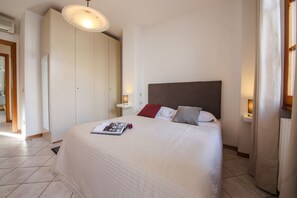 Un dormitorio con cama, lámparas de noche, armario y luz en el techo.