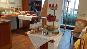 Ruokailutila, jossa on tarjolla buffet, hedelmäkulho ja kakku kakkuvadilla.