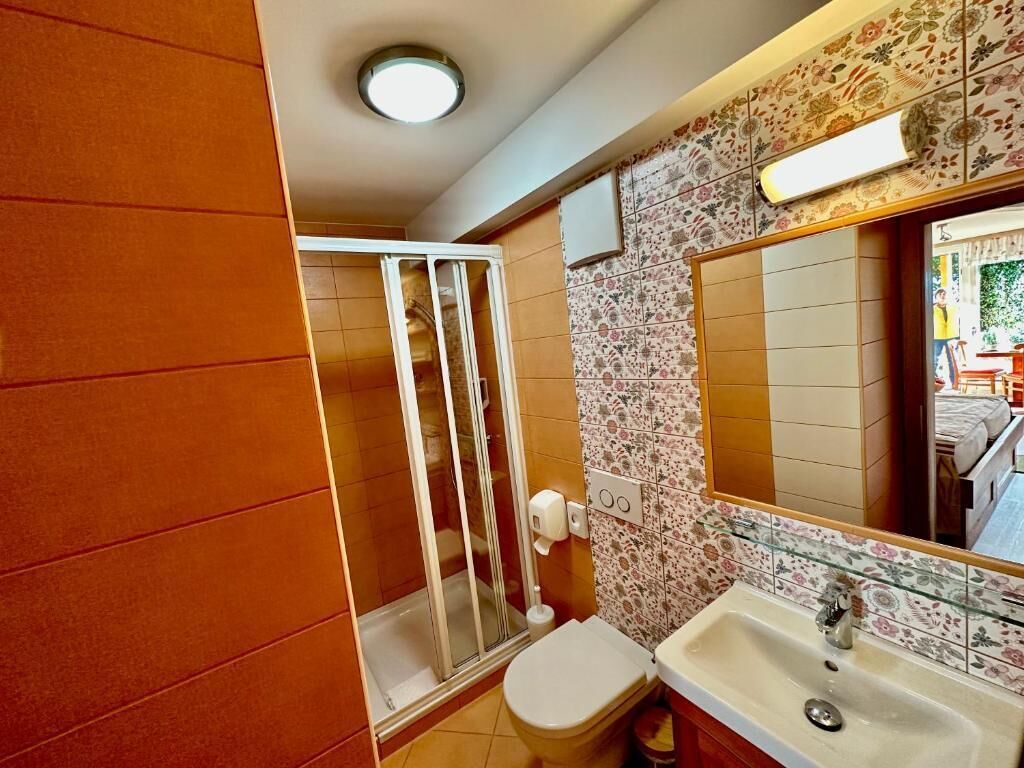 Un bagno con doccia, WC, lavandino e specchio.