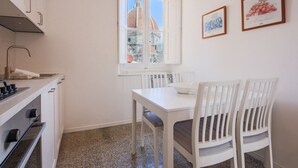 A small kitchen with a window, white cabinets, and a dining table with chairs.
