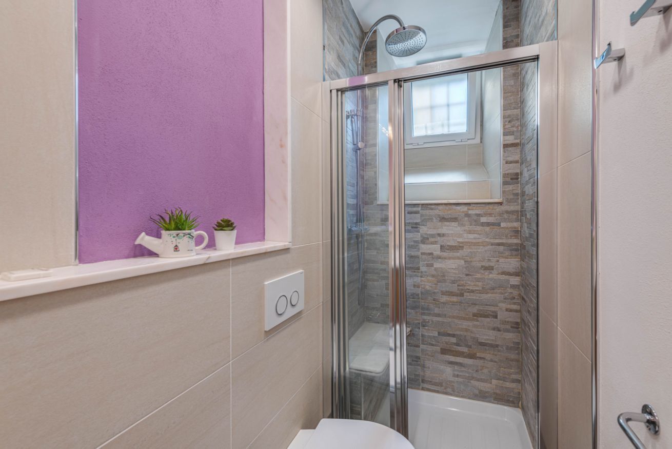 Une salle de bain moderne avec une douche à parois de verre, une baignoire blanche et un mur d’accent violet.