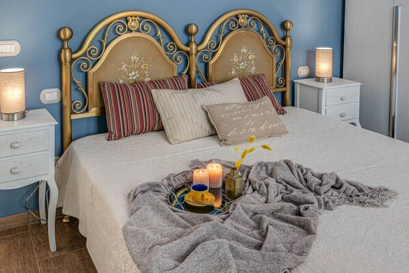 A neatly made bed with a decorative headboard, bedside tables with lamps, and a tray with candles and a cup. - Apartments Florence- Azeglio color (Firenze)