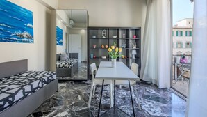 A modern living room with a marble floor, a dining table with chairs, a sofa, a bookshelf, and a large window with curtains. - Apartments Florence- Rosselli Balcony (Firenze)