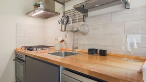 A modern kitchen with a wooden countertop, stainless steel appliances, and a hanging pot rack. - Apartments Florence- Rosselli Balcony (Firenze)