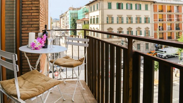 A balcony with a table, chairs, and a view of buildings. - Apartments Florence- Rosselli Balcony (Firenze)