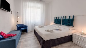 Ein modernes Schlafzimmer mit einem Bett, einem Sessel, einem Nachttisch und einem an der Wand befestigten Fernseher.