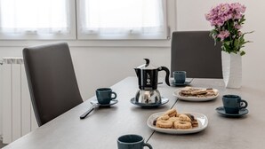 Ein Esstisch mit einer Kaffeemaschine, Tassen und Tellern mit Gebäck.