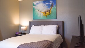 A hotel room with a large bed, a headboard, a nightstand with a lamp, and a painting of a sea turtle on the wall. - 6 Mins Away Cowboy/Ranger Stadium Arlington 1bd (Arlington)