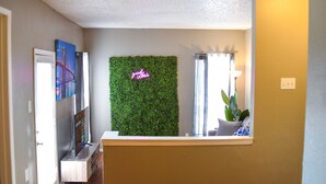 A reception area with a green wall, a neon sign, and a plant. - 6 Mins Away Cowboy/Ranger Stadium Arlington 1bd (Arlington)