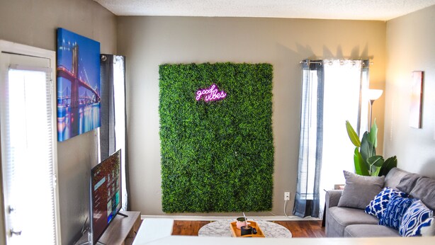 A living room with a green wall, a flat-screen TV, a sofa, and a coffee table. - 6 Mins Away Cowboy/Ranger Stadium Arlington 1bd (Arlington)