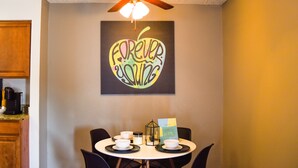 A dining area with a ceiling fan, a table with four chairs, and a wall-mounted sign with the text "FOREVER HOME". - 6 Mins Away Cowboy/Ranger Stadium Arlington 1bd (Arlington)