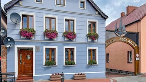 Ein traditionelles europäisches Gebäude mit blauer Fassade, zahlreichen Fenstern mit Blumenkästen und einem Schild mit der Aufschrift 'ALEJA ZEGLARZY'.