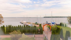 Ein Yachthafen mit vertäuten Booten, ein grüner Kran und ein rotes Tor.