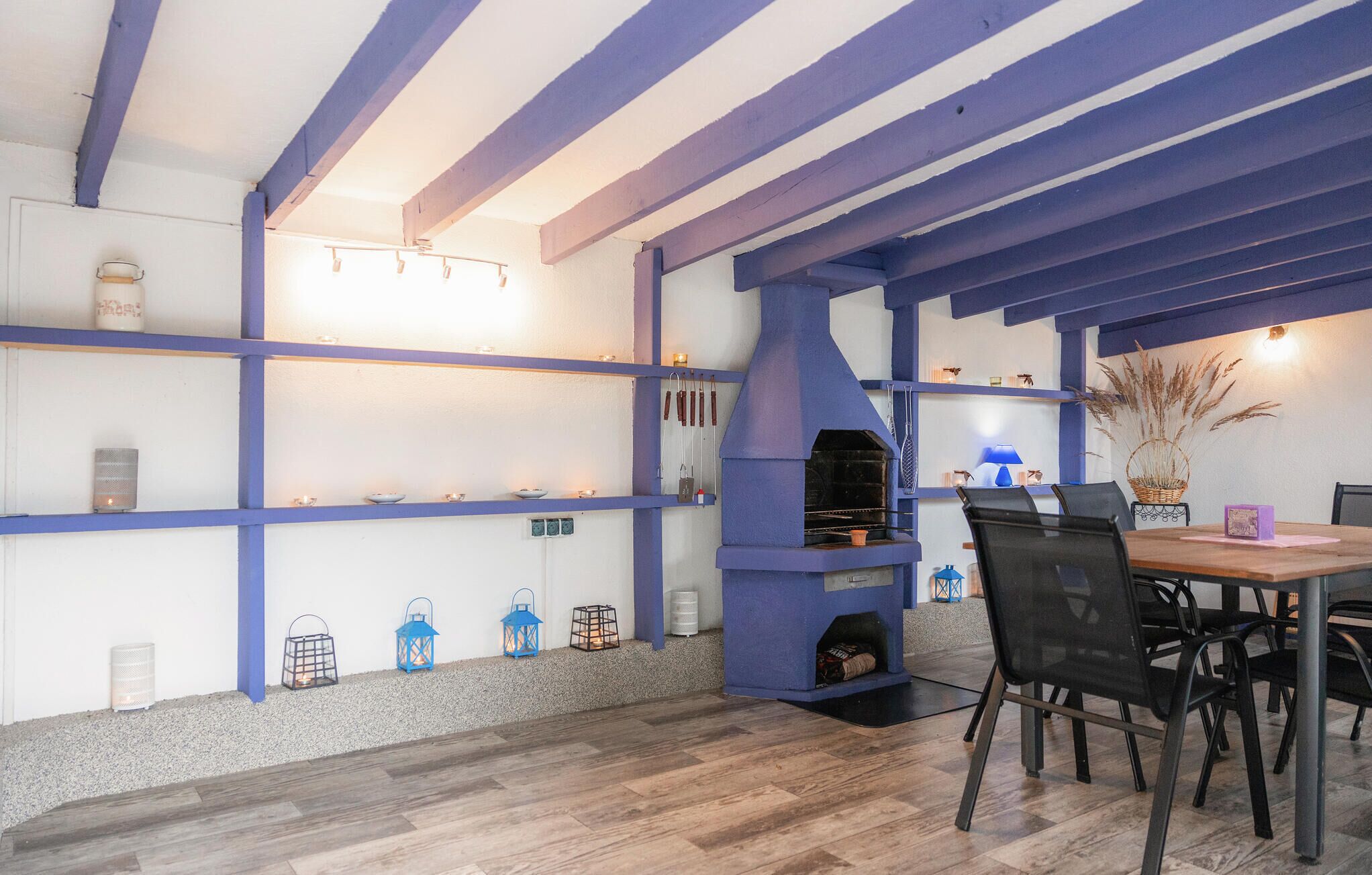 Ein Essbereich mit Holztisch und Stühlen, einer blauen und weißen Farbgestaltung und einem eingebauten Grill.