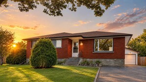 A two-story house with a brick exterior, a front porch, and a well-maintained lawn. - Stylish Newly-Renovated Home in a Central Location (Thunder Bay)