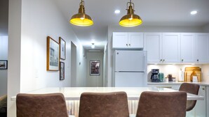 A modern kitchen with white cabinets, a central island with seating, and pendant lighting. - Stylish Newly-Renovated Home in a Central Location (Thunder Bay)
