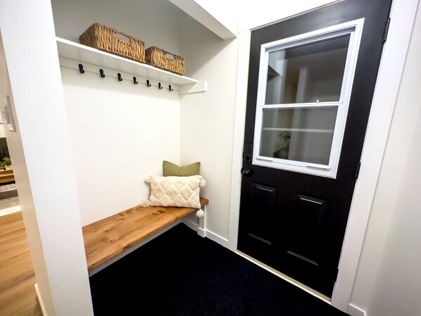 A small entryway with a bench, a door with a window, and shelves with baskets. - Stylish Newly-Renovated Home in a Central Location (Thunder Bay)