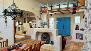 A rustic interior with a stone fireplace, wooden furniture, and a blue door. - Lockout The Oasis | Natural Mineral Hot Springs on 107 Acres (Desert Hot Springs)