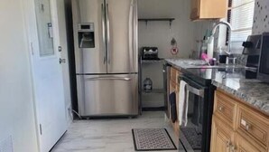 Una cocina compacta con un refrigerador de acero inoxidable, un horno empotrado y armarios de madera.