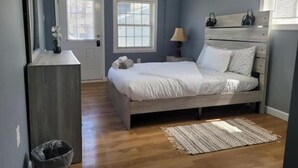 Un dormitorio con cama, mesitas de noche, lámpara y ventana.