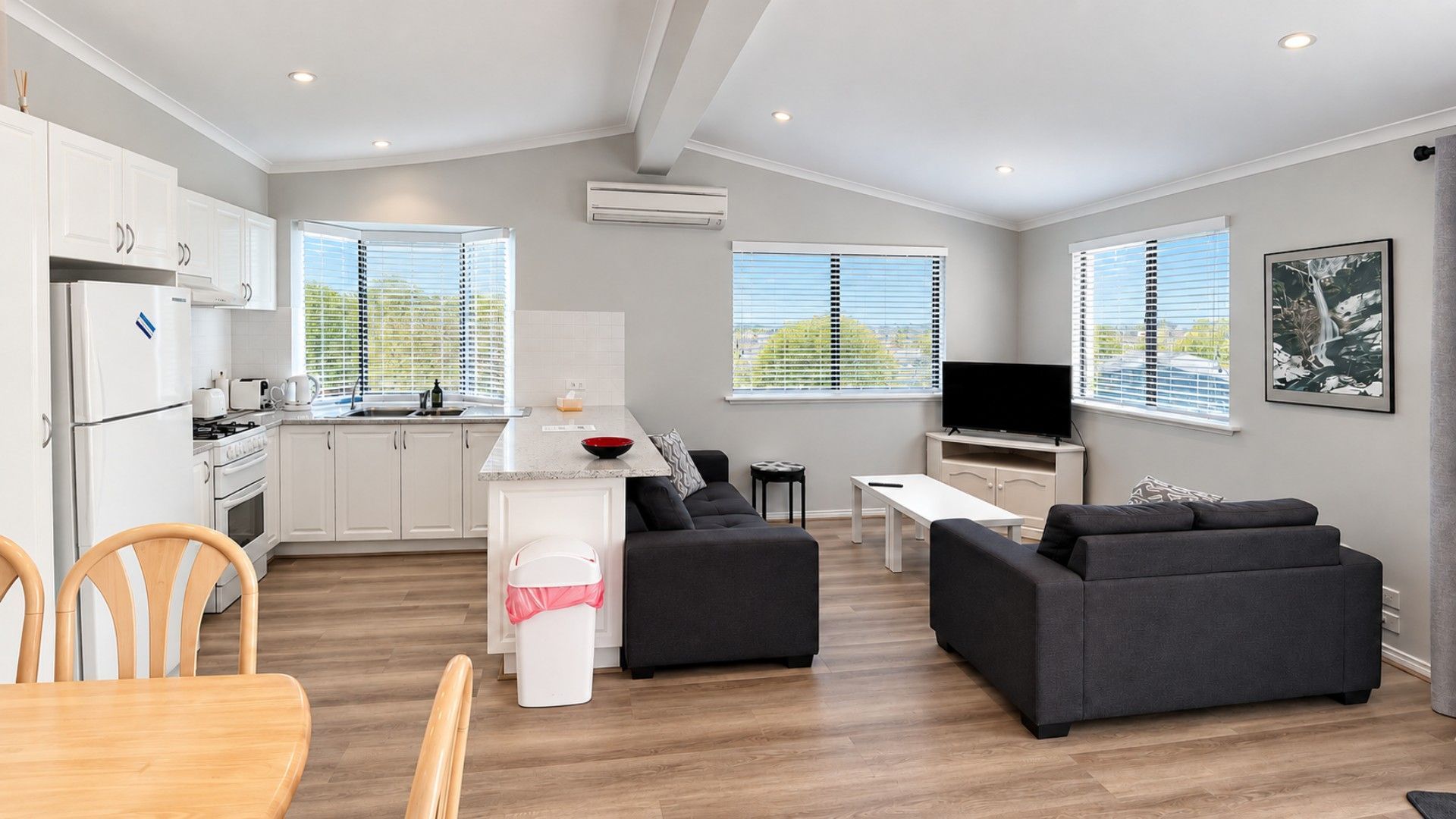 Een modern appartement met een keuken, eethoek, woonkamer en een televisie.