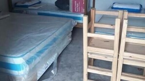 Una cama litera con colchón y una escalera de madera. Hay un libro en la cama y una caja en la parte superior.