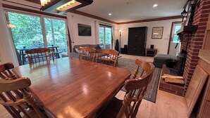 Un vaste espace dédié à la salle à manger, avec une grande table et des chaises en bois, un lustre moderne et une cheminée.
