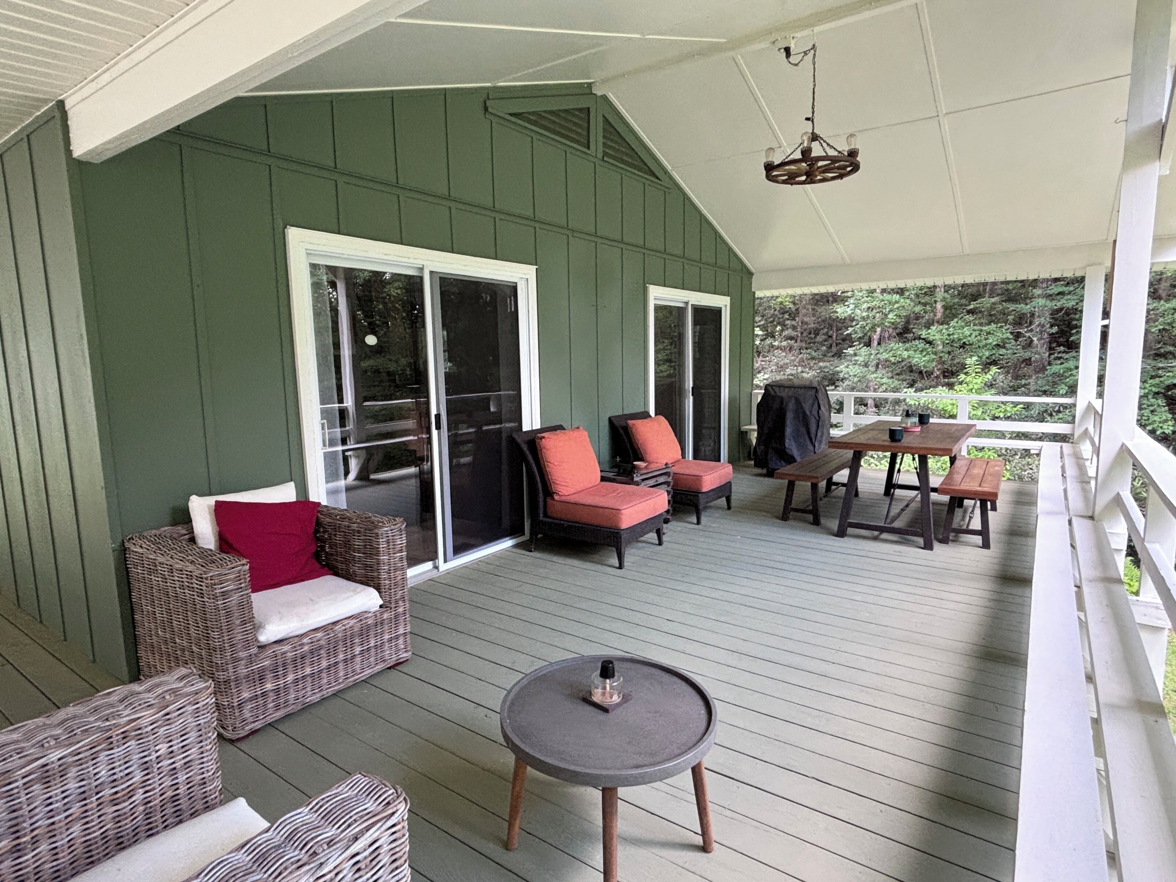 Une véranda couverte avec des meubles en osier, une table et un barbecue.