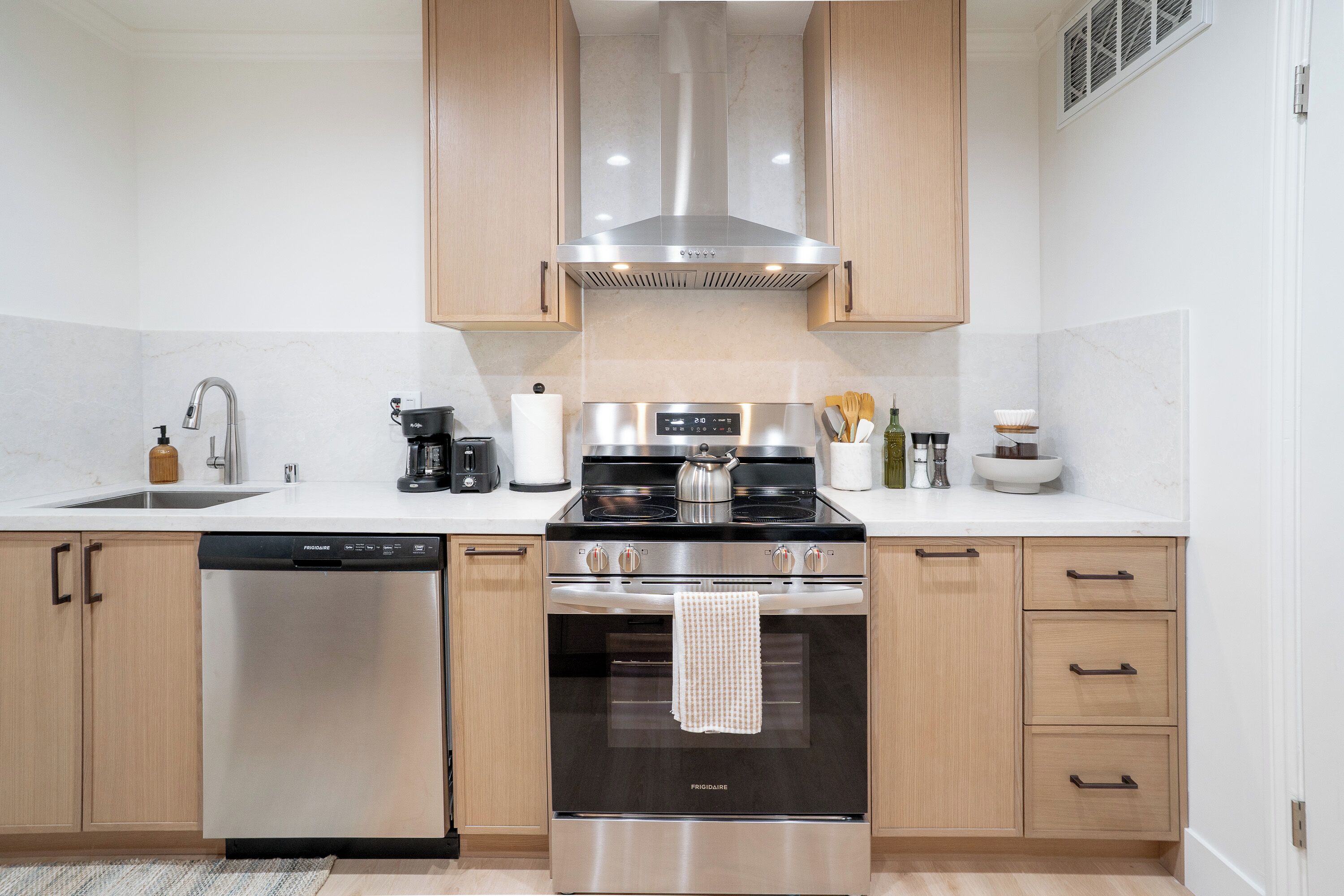 A modern kitchen with stainless steel appliances, wooden cabinets, and a dishwasher.