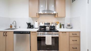 A modern kitchen with stainless steel appliances, wooden cabinets, and a dishwasher.