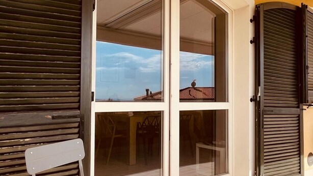 A building with a large glass door, a view of a cityscape, and a balcony with a chair. - S334 - Sirolo, wonderful panoramic three-room apartment (Sirolo)