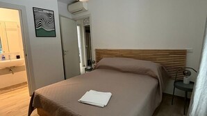 A hotel room with a bed, a bedside table, a lamp, a wall-mounted picture, and a door leading to another room. - S334 - Sirolo, wonderful panoramic three-room apartment (Sirolo)