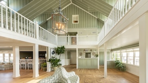 A spacious interior with a high ceiling, a dining area, kitchen, and a seating area with a view. - Poolside King | Private Beach + Award-Winning Spa (Duck)