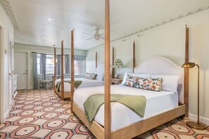 A four-poster bed with a wooden frame and a white headboard, a patterned floor, and a ceiling fan.